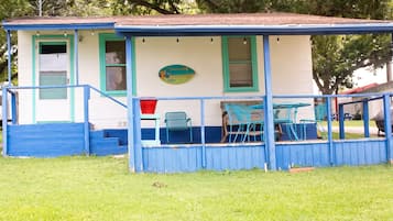 A small, single-story building with a porch and a few chairs.