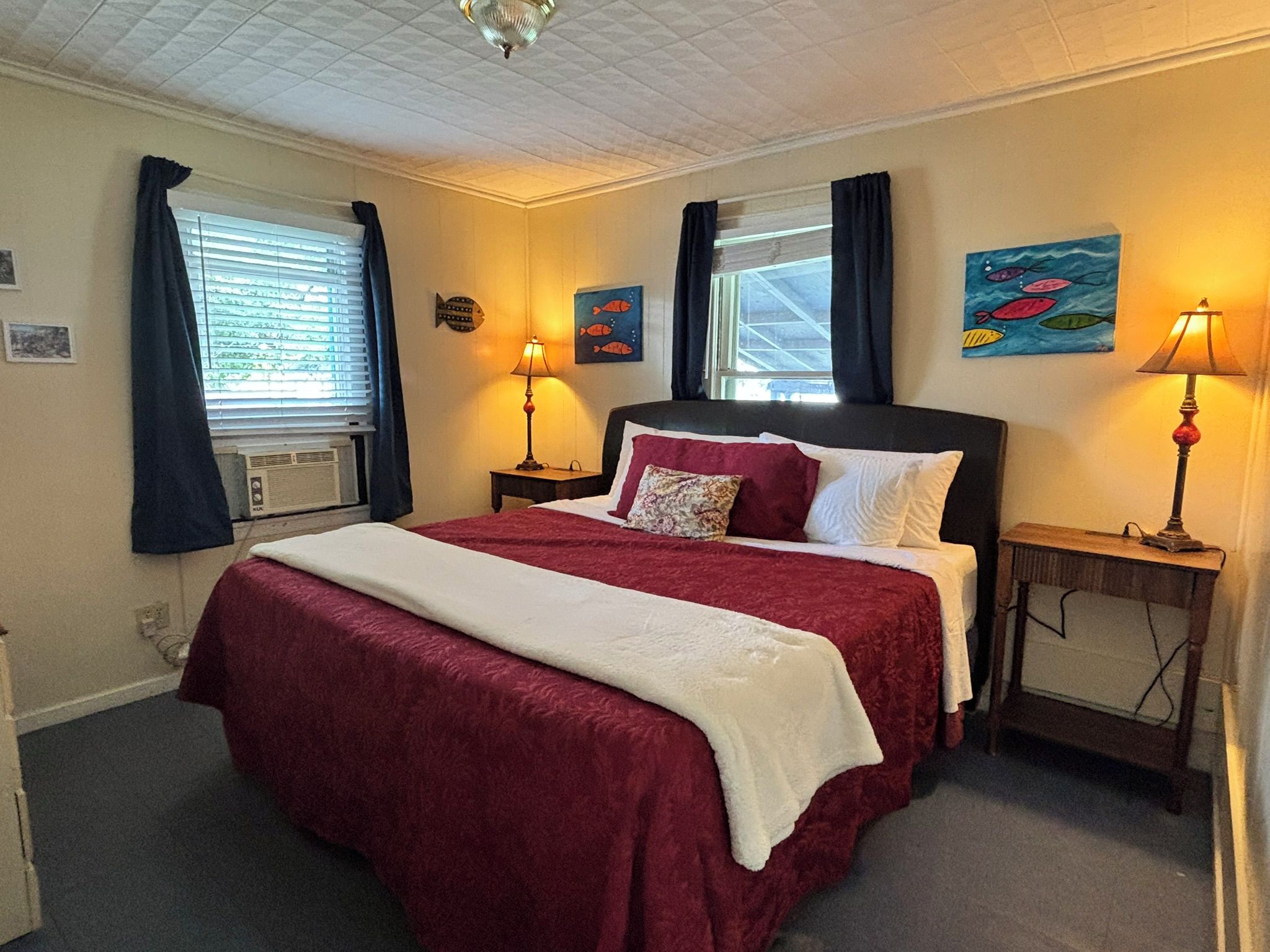 Habitación de hotel con una cama grande, dos mesitas de noche, una ventana con cortinas y decoración en la pared.