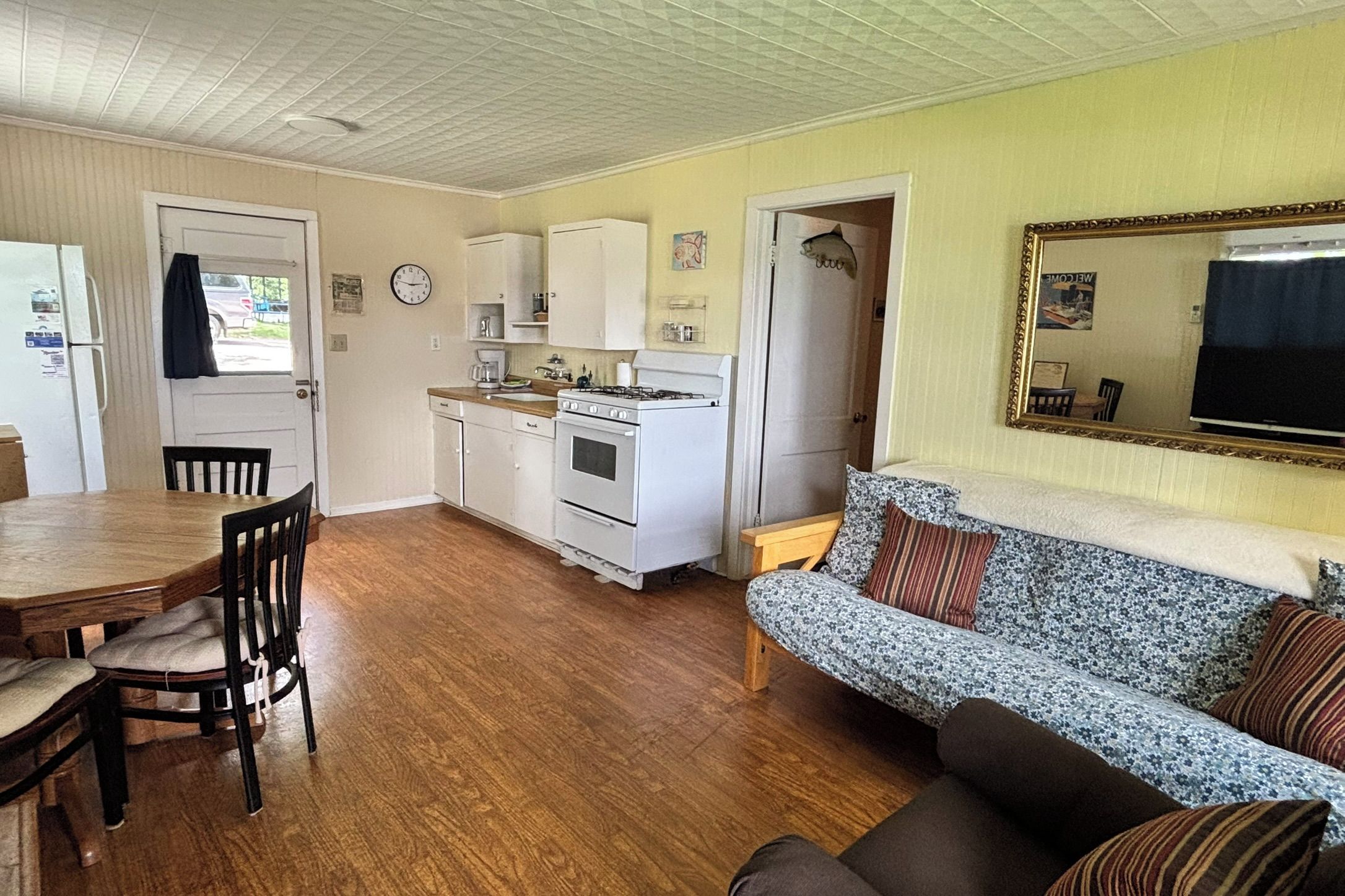 Ett kompakt bostadsutrymme med en matplats, ett litet kök och en soffa.