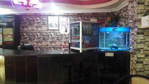 A reception area with a stone wall, a fish tank, and a counter. - Royal Palm Hotel And Suites (Nakuru)