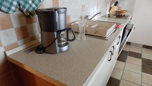 A kitchen with a coffee maker, a glass, and a sink.