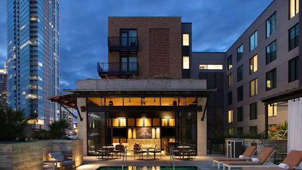 A rooftop pool area with lounge chairs and a bar, surrounded by modern buildings. - Canopy by Hilton Austin Downtown (Austin)