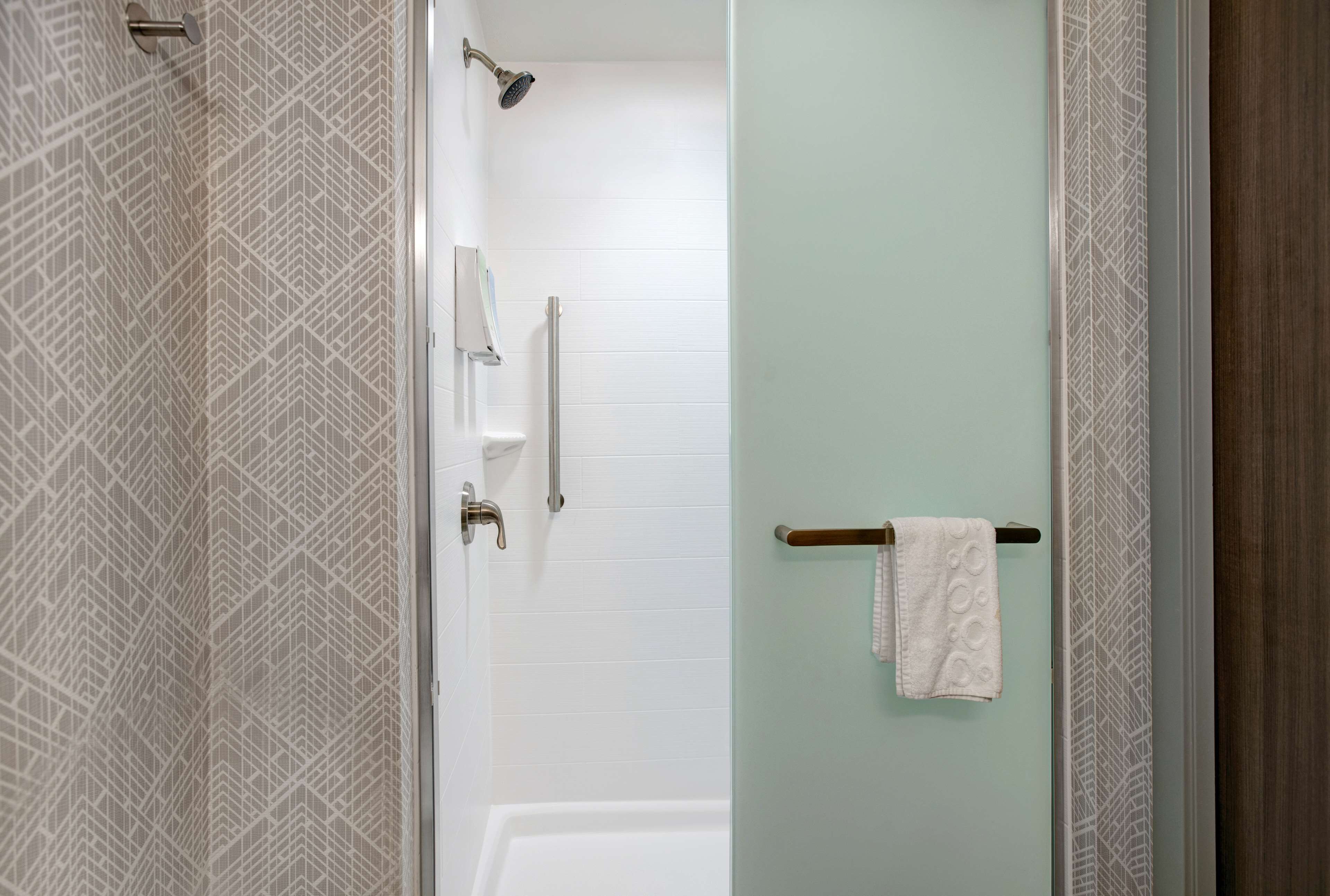 A modern bathroom with a shower, a glass door, and a towel rack.