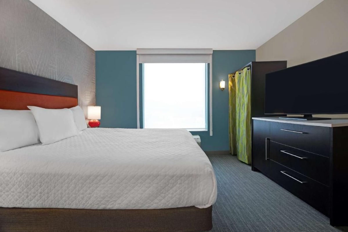 Une chambre d’hôtel avec un lit, une télévision, un bureau et une fenêtre.