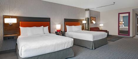 Une chambre d’hôtel avec deux lits, chacun doté d’une tête de lit, de tables de chevet et de lampes.