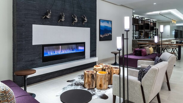 A modern living room with a fireplace, wooden stools, and contemporary furniture.