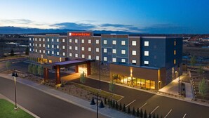 A modern hotel with a flat roof, multiple floors, and a large parking lot.