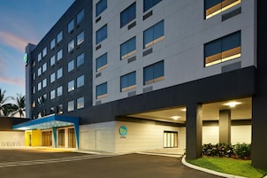 Een modern hotelgebouw met een platte gevel, veel ramen en een blauw entreegebied.