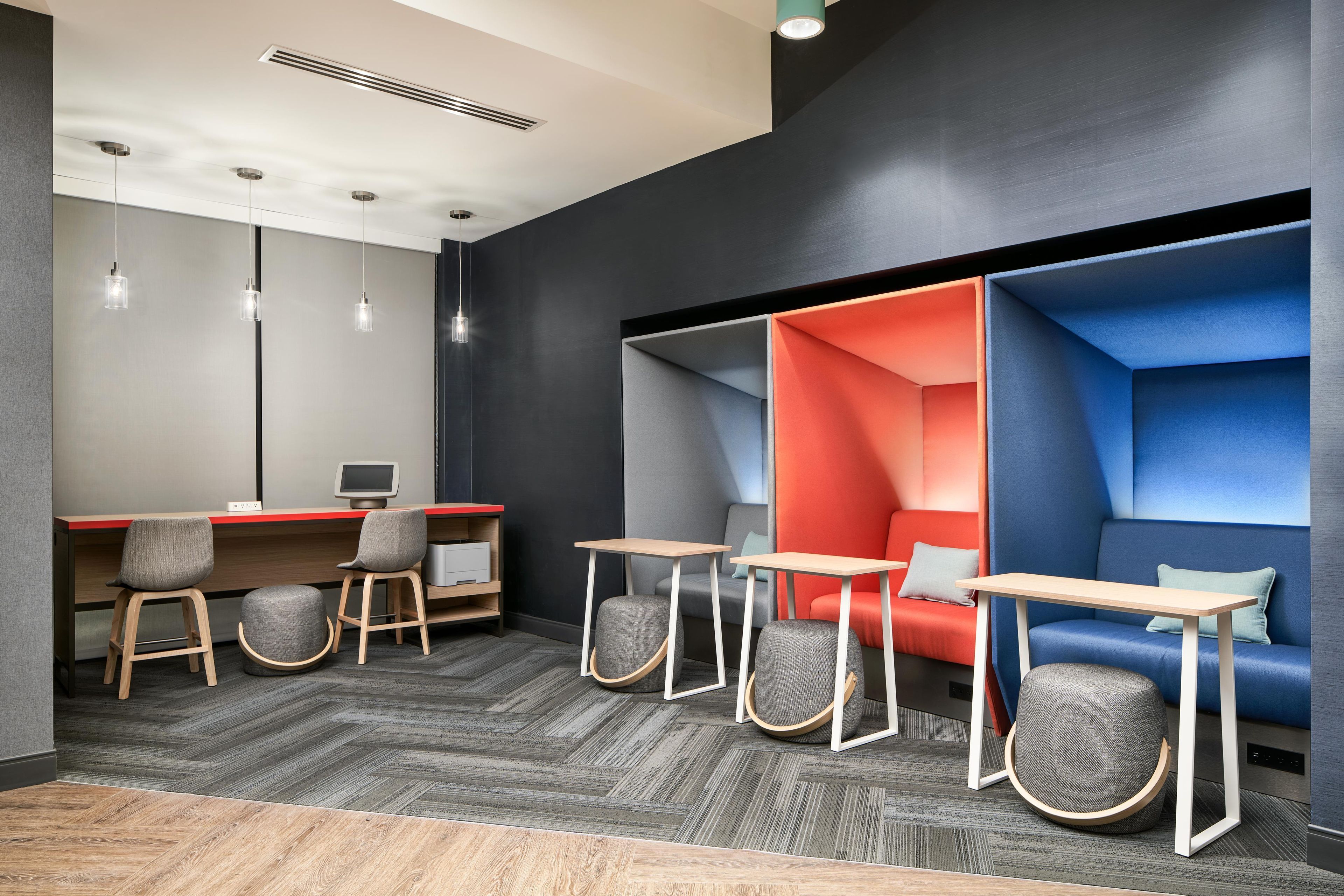 A modern office space with a desk, chairs, and a seating area with a red and blue color scheme.