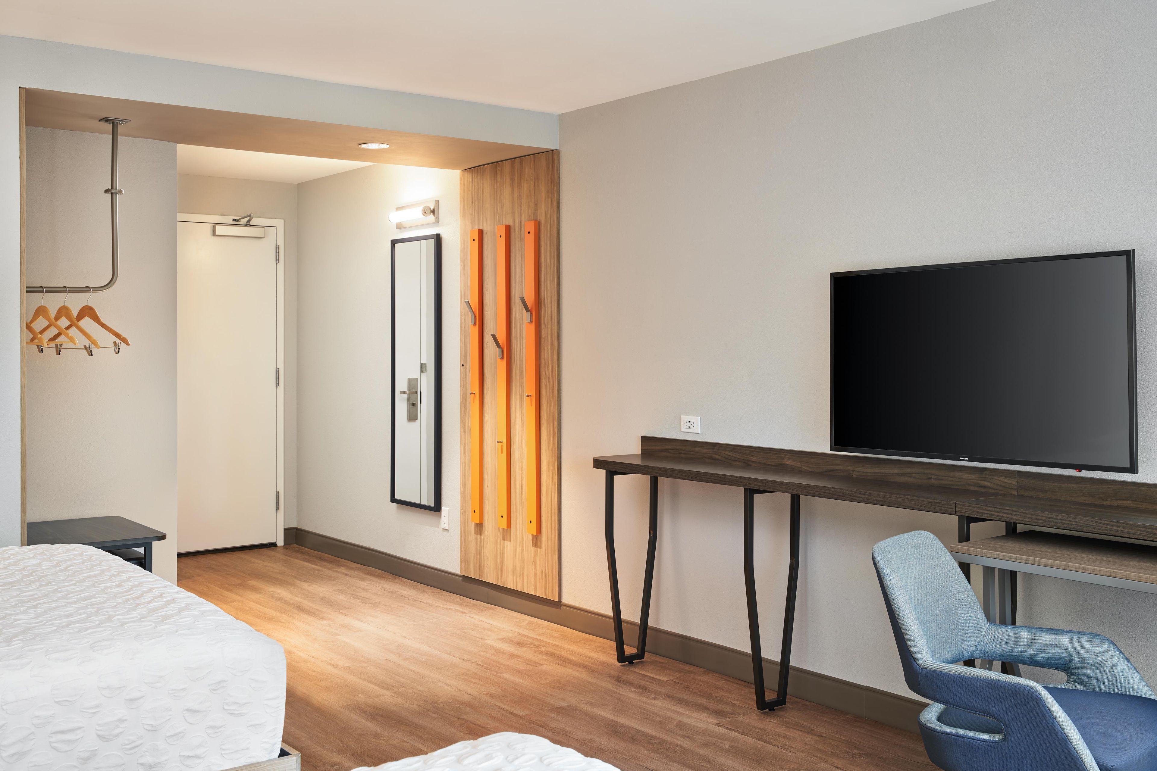 A hotel room with a bed, a desk, a chair, a television, and a wardrobe.