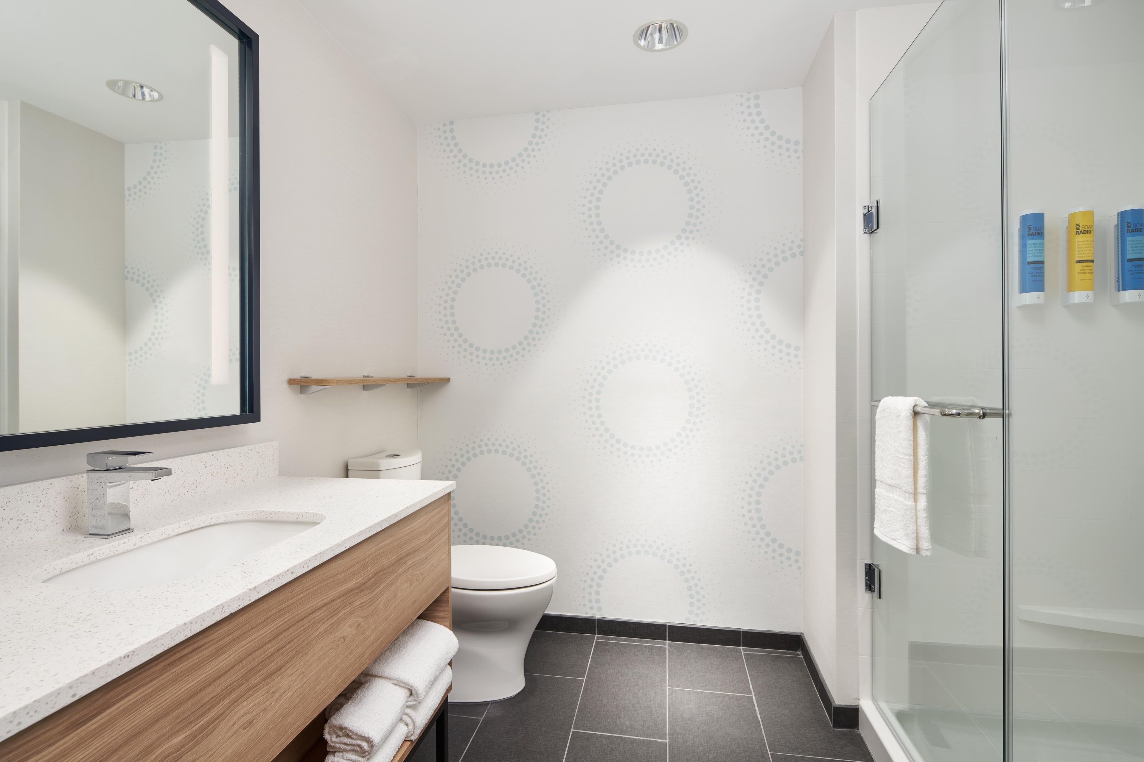 Un baño moderno con un lavamanos blanco, un inodoro y una cabina de ducha con paredes de vidrio.