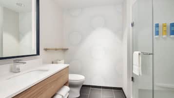 Un baño moderno con un lavamanos blanco, un inodoro y una cabina de ducha con paredes de vidrio.