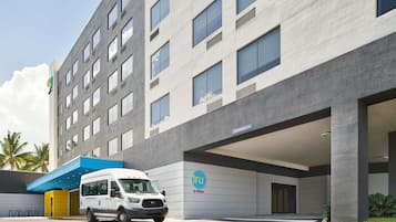 A modern hotel building with a white facade, multiple windows, and a blue entrance canopy.