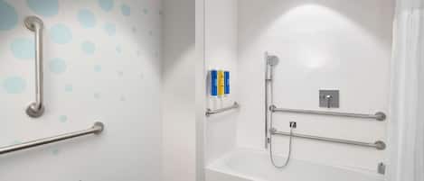 A modern bathroom with a white bathtub, grab bars, and a shower with a handheld showerhead.