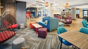 A modern lounge area with seating arrangements, a coffee station, and a visible kitchen area.