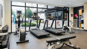 A gym with treadmills, weight machines, and a bench press. - Tru By Hilton Ft. Lauderdale Airport (Dania Beach)