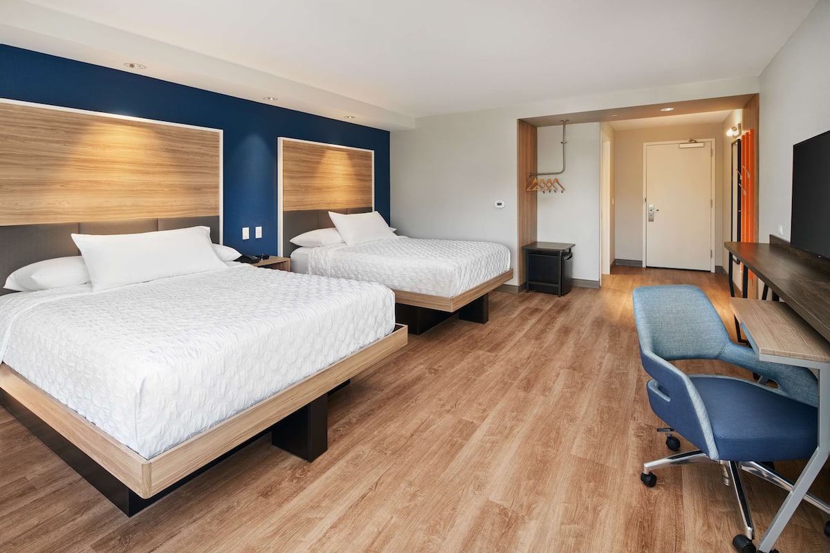 A hotel room with two beds, a desk, and a chair.