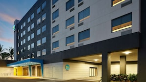 A modern hotel building with a flat facade, multiple windows, and a well-lit entrance area.