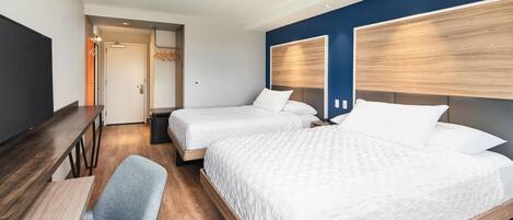 Una habitación de hotel con dos camas, un escritorio y una silla.