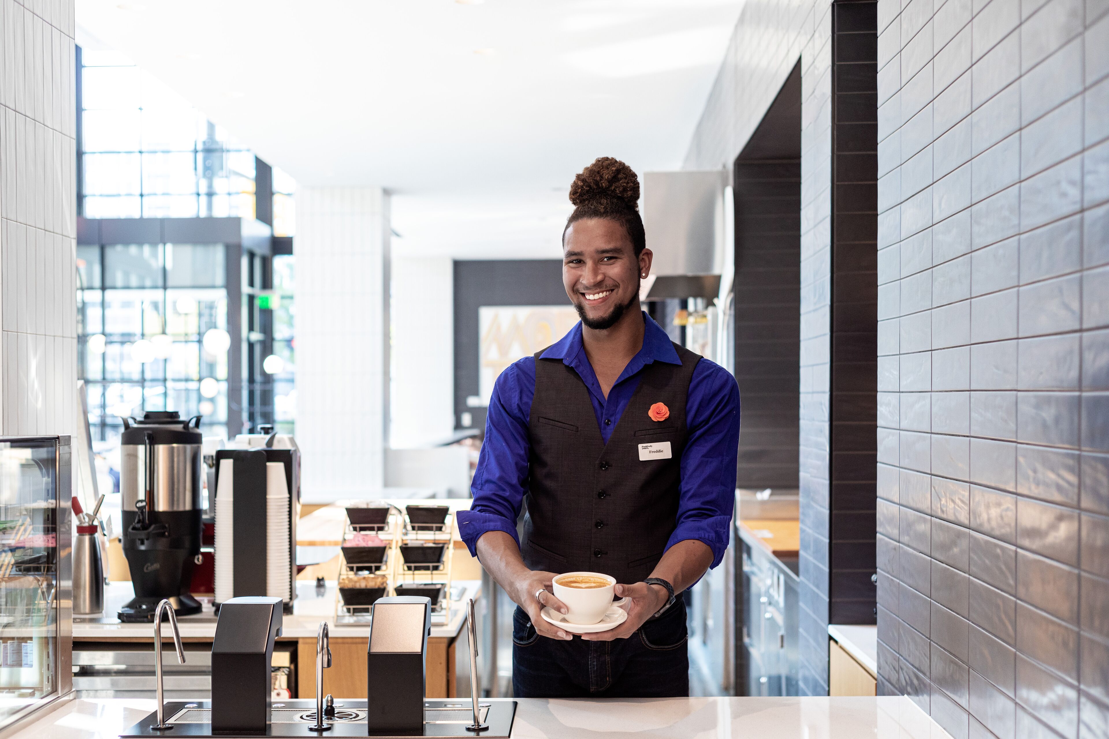 A modern coffee shop interior with a barista holding a cup of coffee.