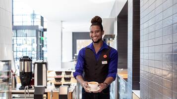 A modern coffee shop interior with a barista holding a cup of coffee.