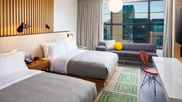 Habitación de hotel con dos camas, un sofá, una mesa de comedor y un televisor.