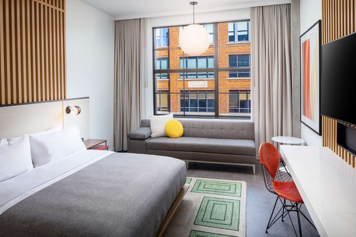 Una habitación de hotel moderna con una cama grande, un sofá, una mesa de comedor y un televisor.