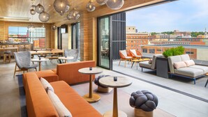 Un espace de détente moderne, doté de sièges, de tables et offrant une vue sur le paysage urbain.