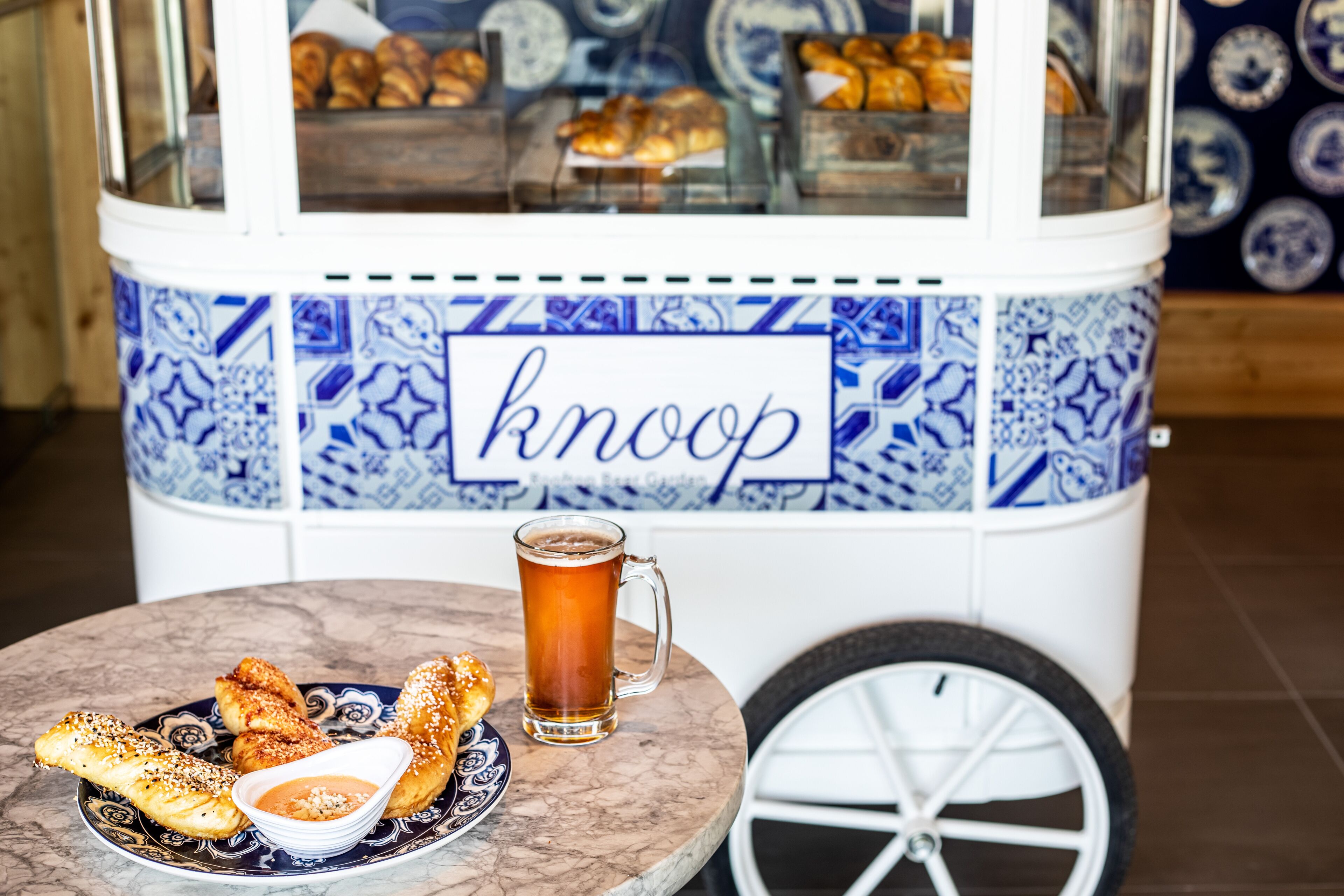 Un carrito de comida con la palabra "knoop", un plato de comida y una jarra de cerveza.