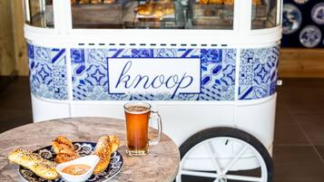 Un carrito de comida con la palabra "knoop", un plato de comida y una jarra de cerveza.