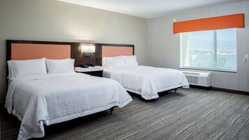 A hotel room with two beds, a large window, and a view of the city.