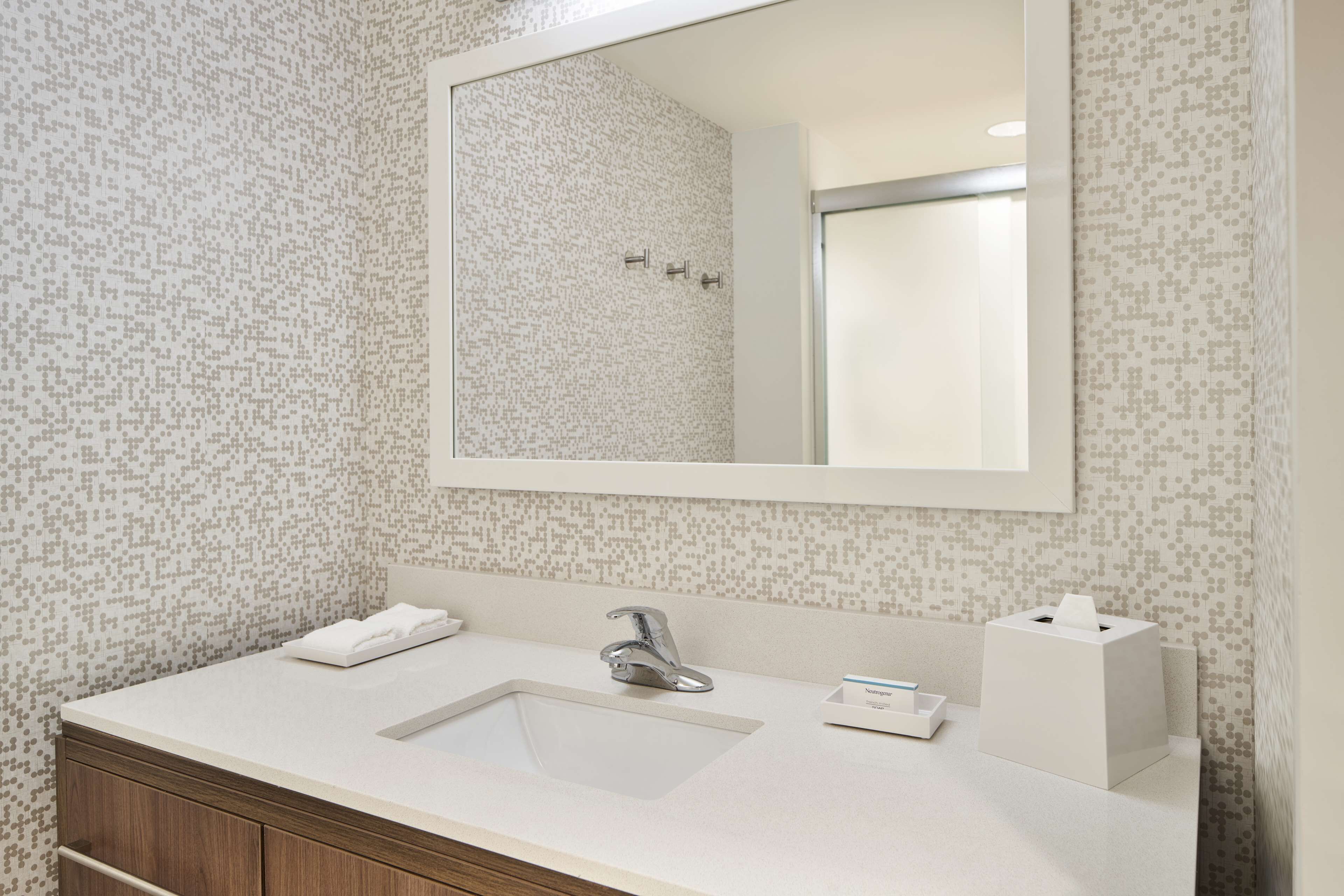 A bathroom with a white sink, a mirror, and a patterned wall.