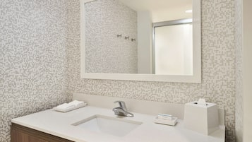 Un baño con lavamanos blanco, un espejo y un papel tapiz estampado.