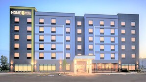 A multi-story hotel with a modern design, featuring a prominent entrance with a covered walkway and a parking lot in front. - Home2 Suites by Hilton Palm Bay Melbourne I 95 (Palm Bay)