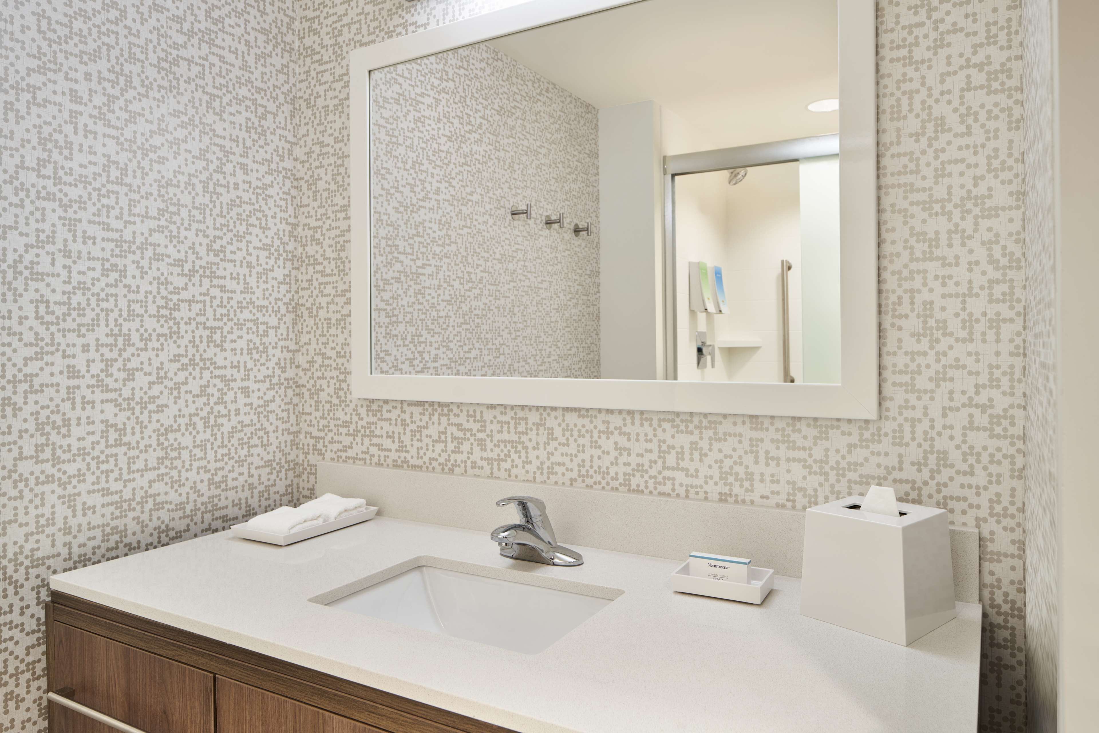 A bathroom with a white sink, a mirror, and a patterned wall.