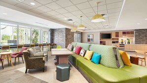 A modern lounge area with a green sofa, armchairs, and a dining table. - Home2 Suites by Hilton Palm Bay Melbourne I 95 (Palm Bay)