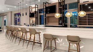 A modern kitchen with a bar area, featuring pendant lights, bar stools, and a large island. - Hilton Garden Inn Ocala Downtown (Ocala)