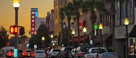 Una calle flanqueada por vehículos estacionados y farolas iluminadas.