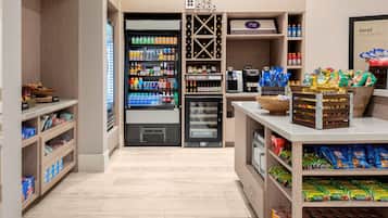 A modern retail space with a refrigerated section, shelves stocked with snacks, and a coffee machine.