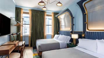 A hotel room with two beds, a desk, a chair, a TV, and a large window with curtains.