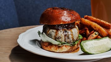 A burger with fries and a slice of cucumber on a white plate.