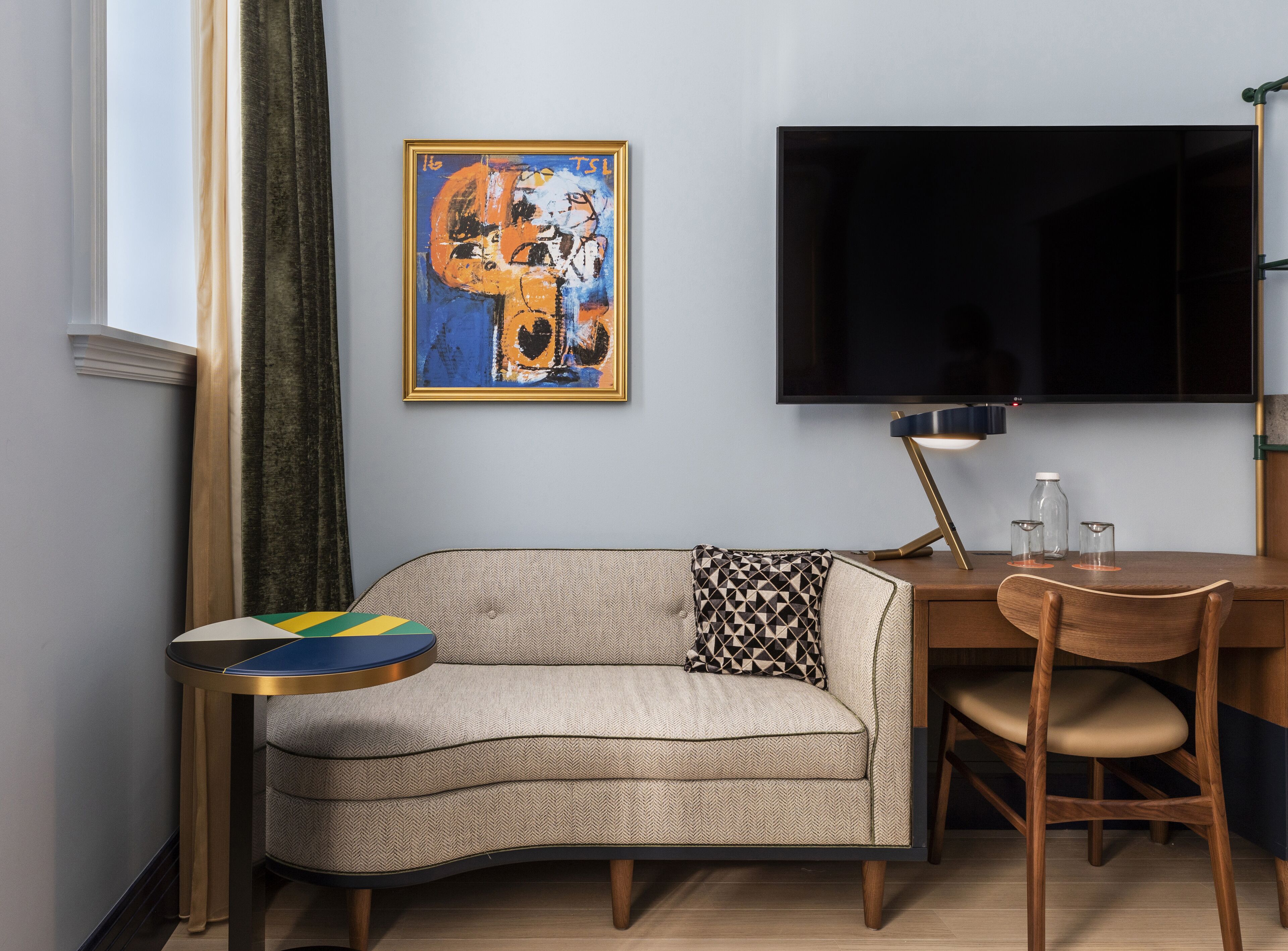 A modern living room with a sofa, a coffee table, a TV, and a painting on the wall.