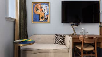 A modern living room with a sofa, a coffee table, a TV, and a painting on the wall.