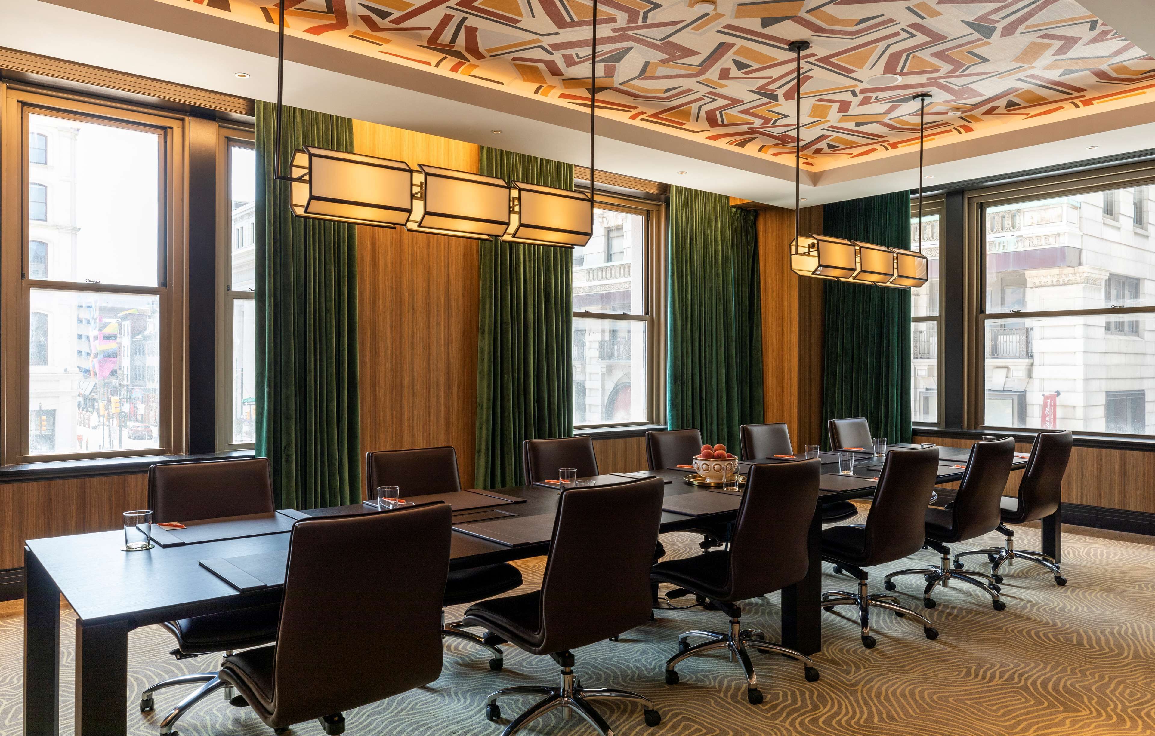A conference room with a long table, chairs, and a patterned ceiling.