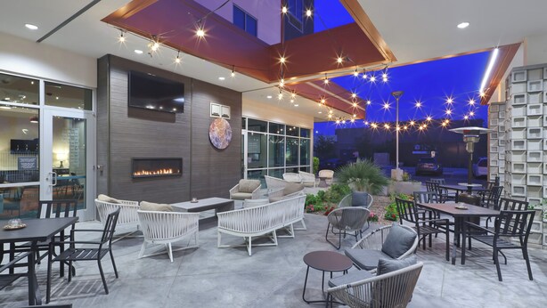 An outdoor patio area with seating arrangements, a fireplace, and string lights. - Hilton Garden Inn Chandler Downtown (Chandler)