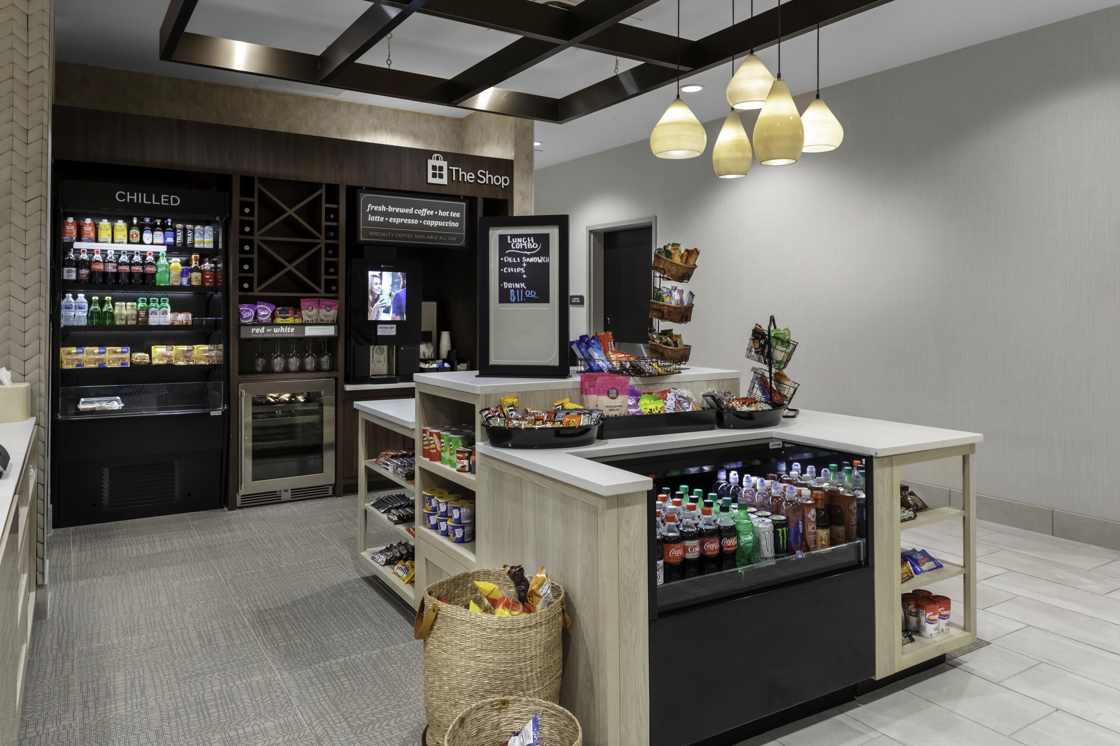 Un espacio comercial moderno con una sección de bebidas frías, una barra de café y un mostrador de aperitivos.