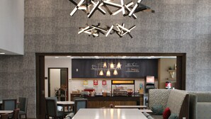 A modern restaurant with a long dining table, booths, and a bar area.