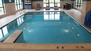 An indoor swimming pool with clear water, marked depth lines, and lounge chairs.