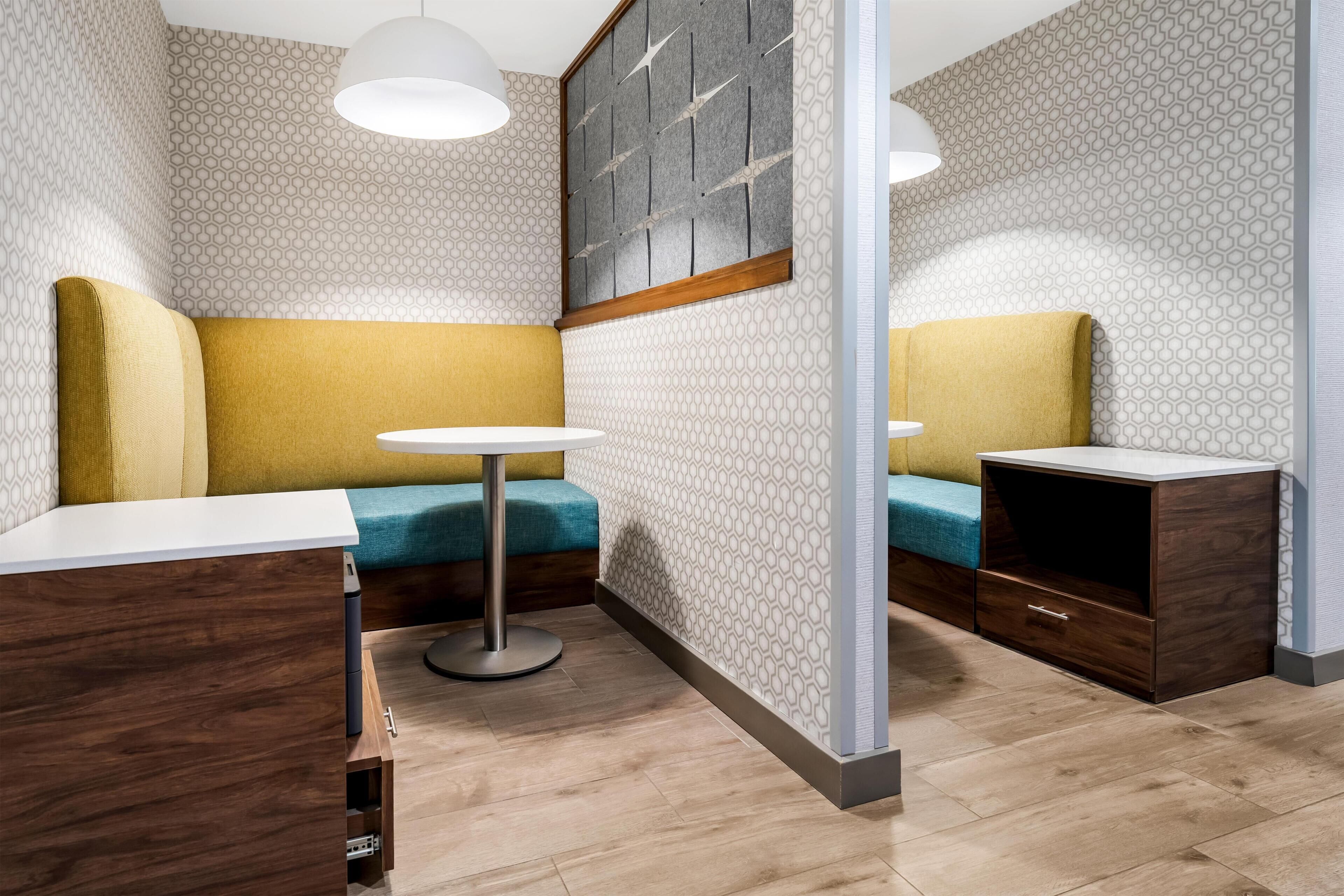 Un área de descanso con sofás, una mesa redonda, bancos acolchados y un mueble de madera.