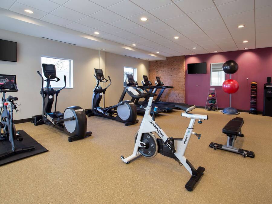 Un gimnasio con bicicletas estáticas, cintas de correr y una máquina de remo.